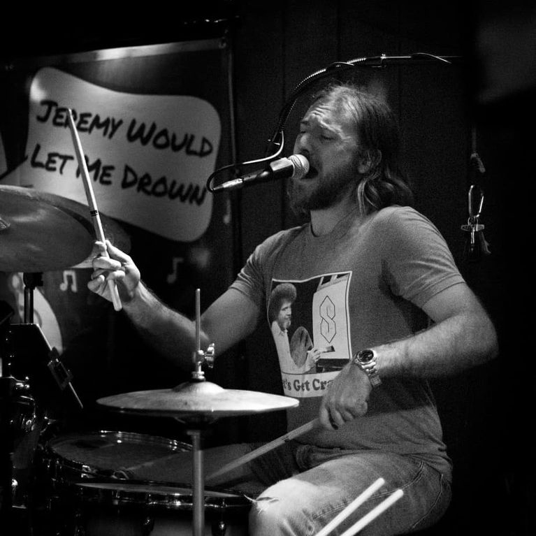 Jeff Wheeler singing while playing drums.
